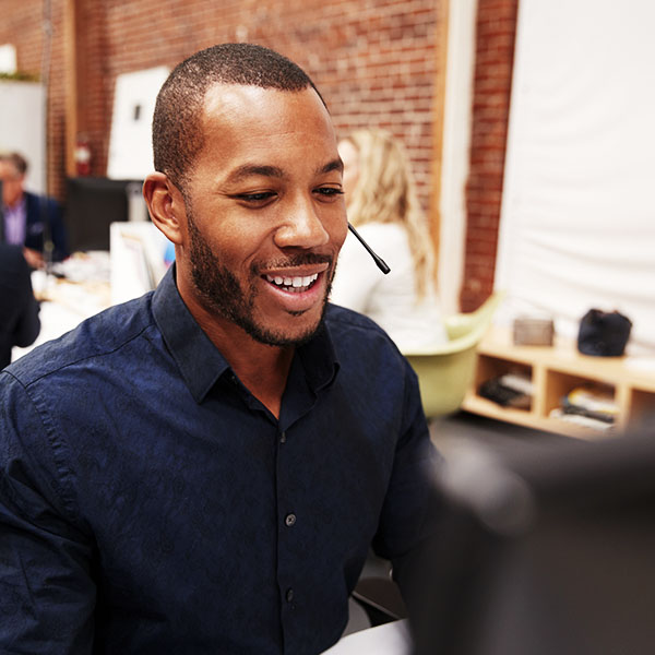 A businessman on a bluetooth headset conducts a phone call on his VoIP phone system.