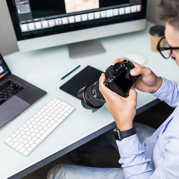 Cloud Backup - A photographer is sitting at his computer downloading images from his camera.